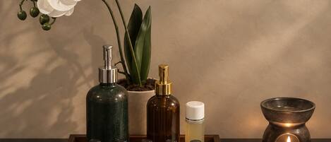 A tray with essential oils, a candle, and a potted plant on a table.
