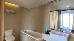 A modern bathroom with a toilet, bathtub, and two sinks. - Paragon Hotel Seminyak (Keroboken Kelod)