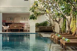 Una piscina al aire libre, sombrillas, sillones reclinables de piscina