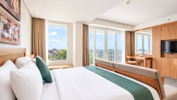 A hotel room with a large bed, a desk, a TV, and a balcony with a city view.