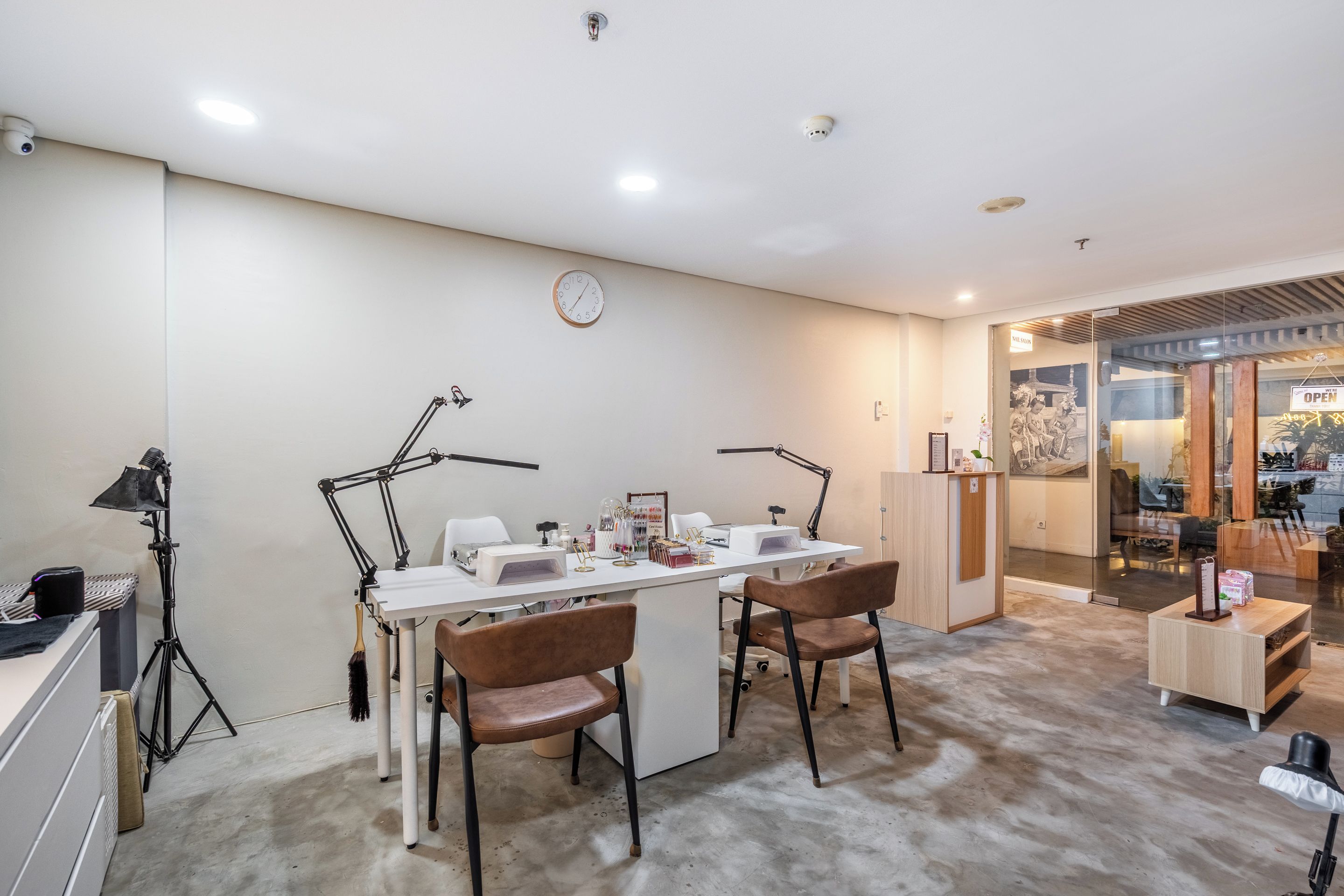 A room with a desk, two chairs, a clock, and a salon sign.