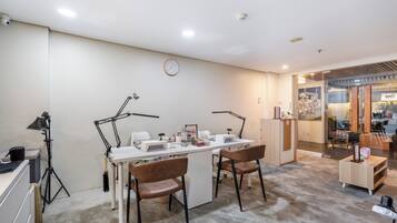 A room with a desk, two chairs, a clock, and a salon sign.