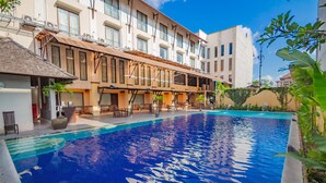 A hotel with a swimming pool, outdoor seating, and a covered patio area. - Grand Santhi Hotel (Denpasar)