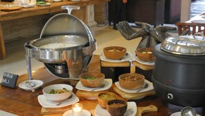 A buffet setup with various dishes and a large pot of rice. - Grand Santhi Hotel (Denpasar)