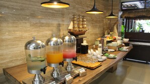 A buffet setup with various food items and a ship model. - Grand Santhi Hotel (Denpasar)