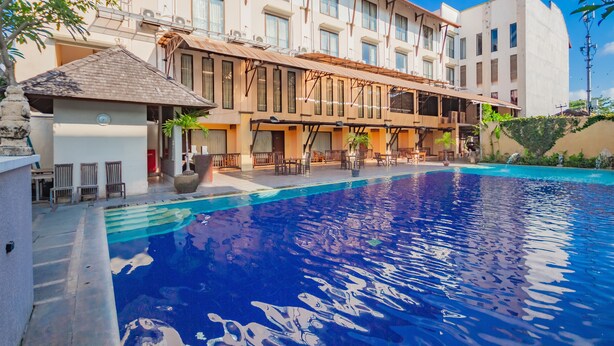 A hotel with a swimming pool, outdoor seating, and a covered patio area. - Grand Santhi Hotel (Denpasar)