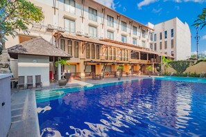 A hotel with a swimming pool, outdoor seating, and a covered patio area. - Grand Santhi Hotel (Denpasar)