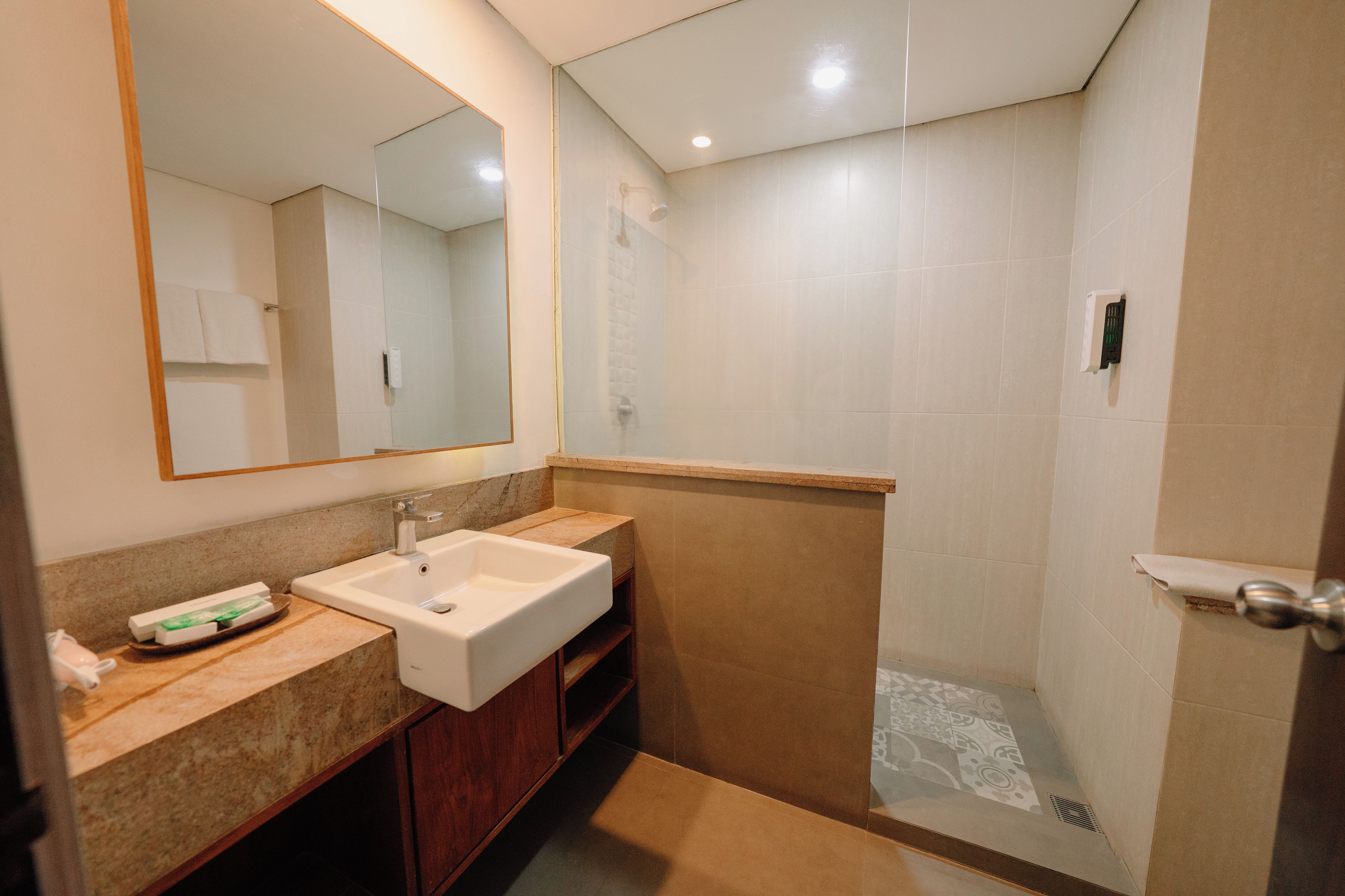 A bathroom with a sink, mirror, and shower.