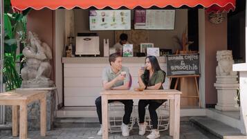 Ett kafé med ett träbord och stolar, en menytavla och en staty i sten.