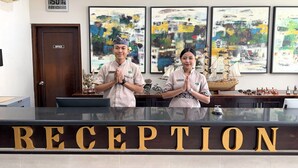 A reception area with a digital clock, abstract paintings, and a ship model. - Grand Santhi Hotel (Denpasar)