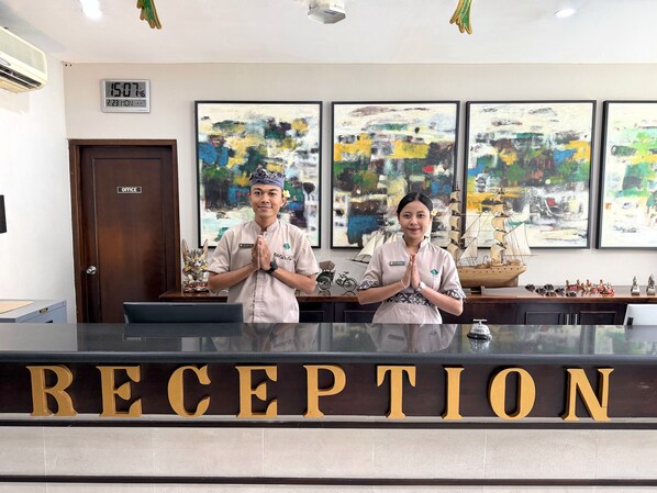 A reception area with a digital clock, abstract paintings, and a ship model. - Grand Santhi Hotel (Denpasar)
