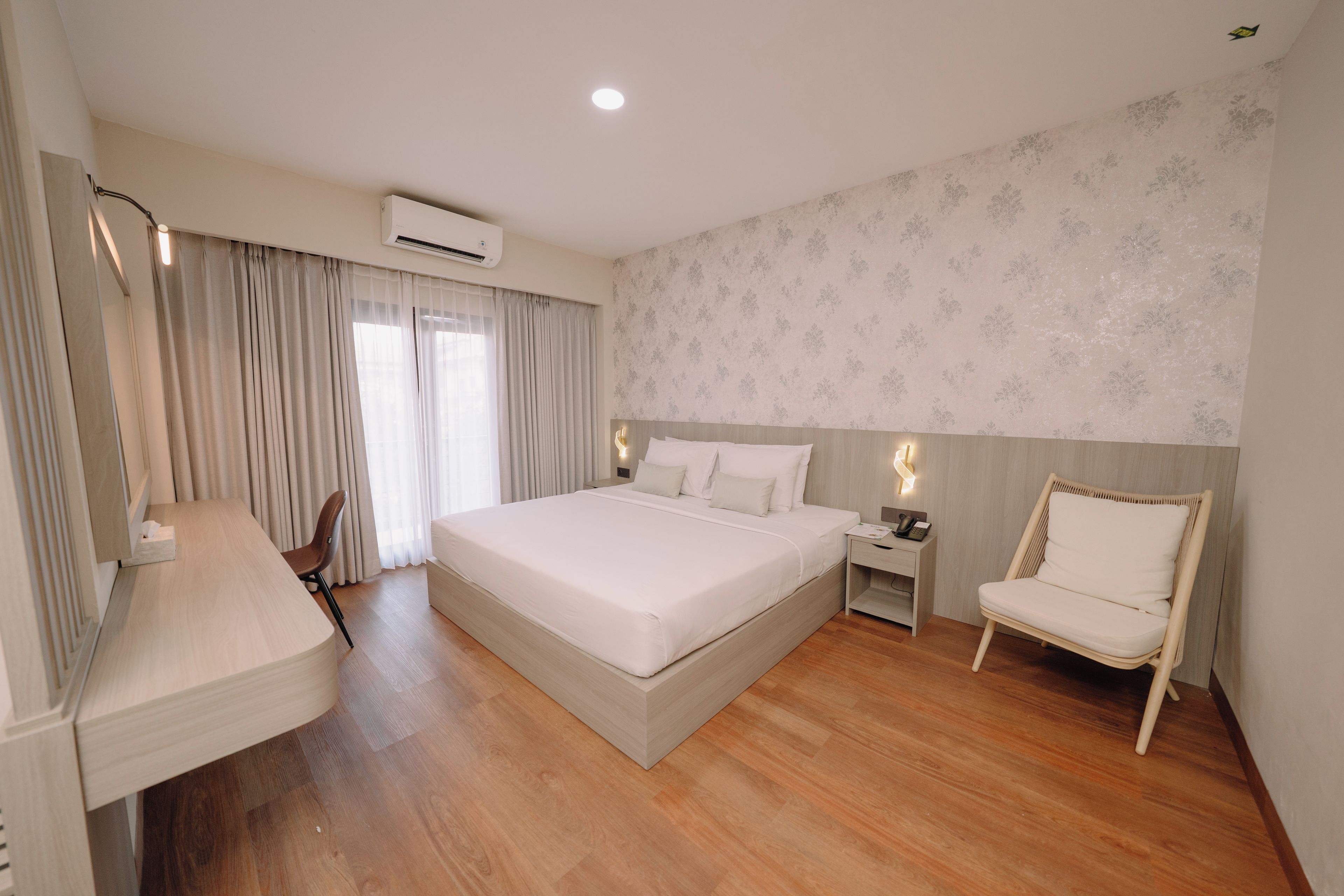 Una habitación de hotel moderna con una cama grande, un escritorio, una silla y una mesita de noche.