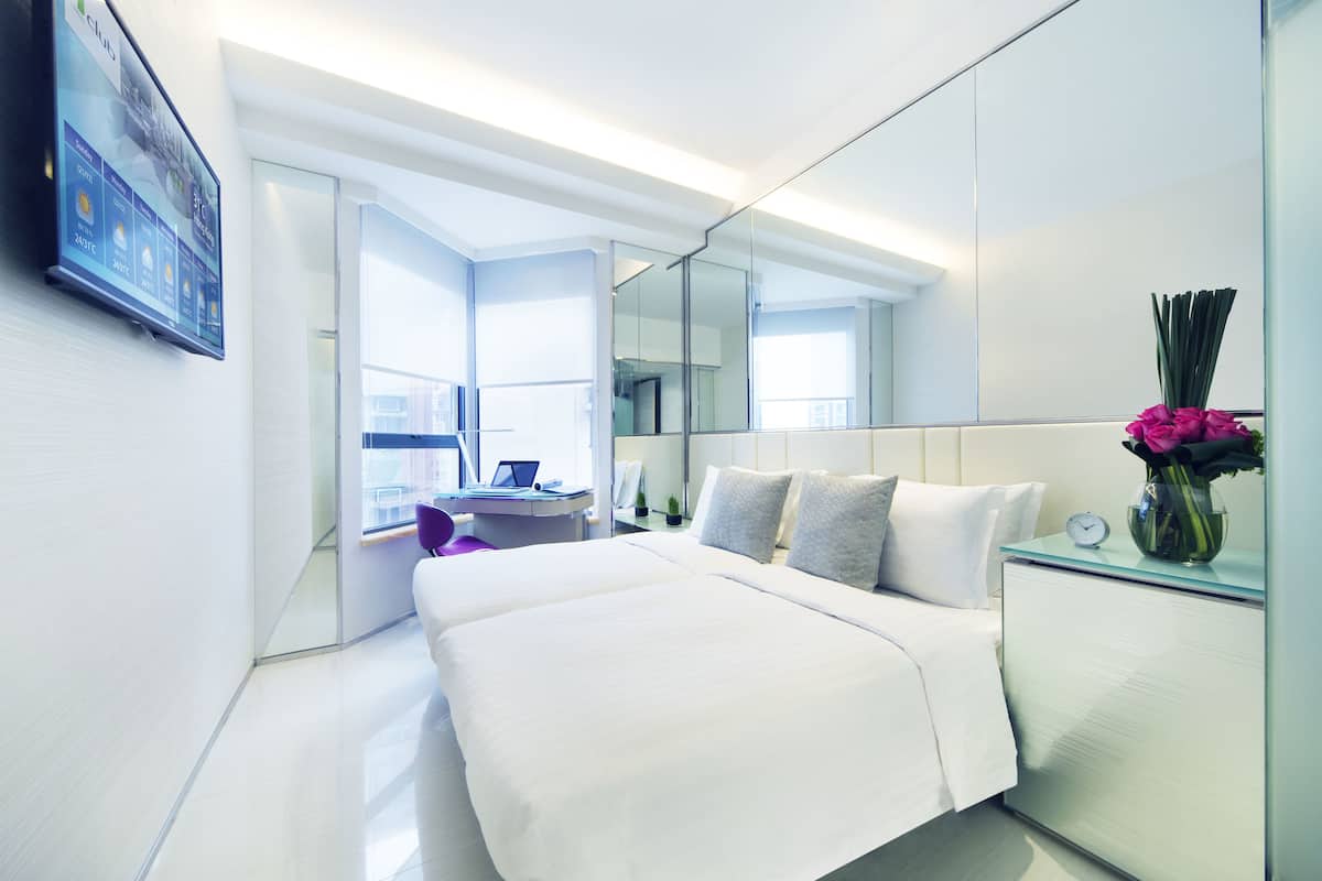 Una habitación de hotel moderna con una cama grande, un escritorio y un espejo.