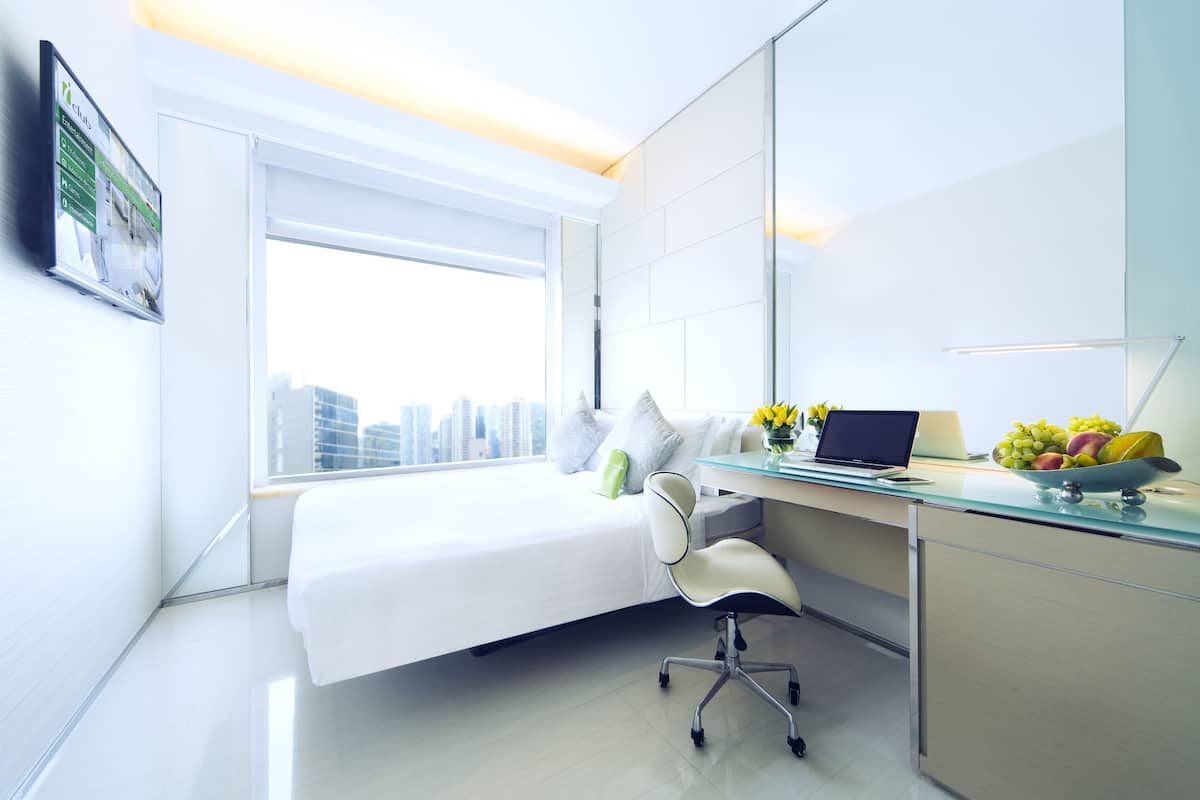 Habitación de hotel moderna con cama, escritorio y vista a la ciudad.
