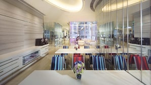A modern, well-lit indoor space with a central dining table, chairs, and a vase of flowers.