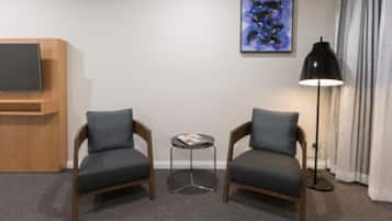 A room with two armchairs, a small table, a television, and a floor lamp.