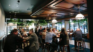 A restaurant interior with wooden ceiling, bar area, and large windows. - Avenue Hotel Canberra (Braddon)