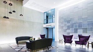 A modern lobby with a sofa, armchairs, and a patterned rug. - Avenue Hotel Canberra (Braddon)