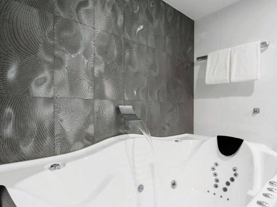 A modern bathroom with a freestanding bathtub, a towel rack, and a textured wall.