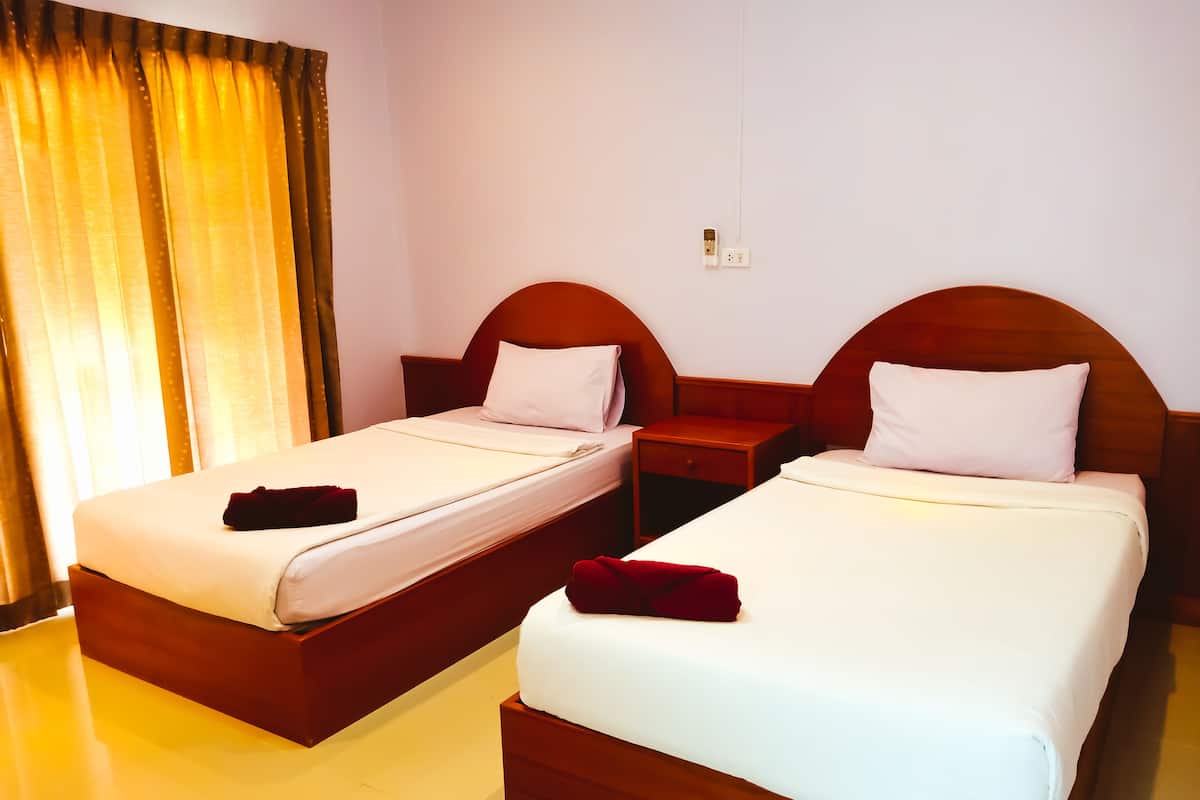 Two single beds with wooden headboards, a nightstand, and a power outlet on the wall.