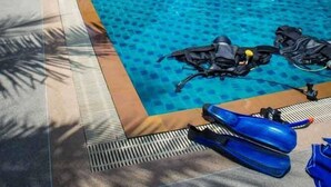 A swimming pool with diving gear and a lifebuoy, surrounded by a building with a red roof and a thatched roof structure. - Hin Bhai Resort (Ko Pha-ngan)