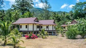 A bungalow-style hotel with a red-tiled roof, surrounded by lush greenery and palm trees. - Hin Bhai Resort (Ko Pha-ngan)