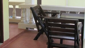 A dining area with a table and chairs, a window with curtains, and a tiled floor. - Hin Bhai Resort (Ko Pha-ngan)