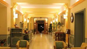 A hotel lobby with a long, ornate corridor, multiple seating areas, and various decorative elements. - Hotel Croce di Savoia (Reggello)
