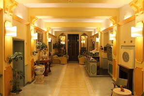 A hotel lobby with a central staircase, multiple seating areas, and decorative plants.
