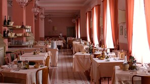A long dining hall with tables set for a meal, featuring a patterned floor and pink walls. - Hotel Croce di Savoia (Reggello)