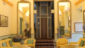 A hotel lobby with a staircase, two large mirrors, and a piano. - Hotel Croce di Savoia (Reggello)