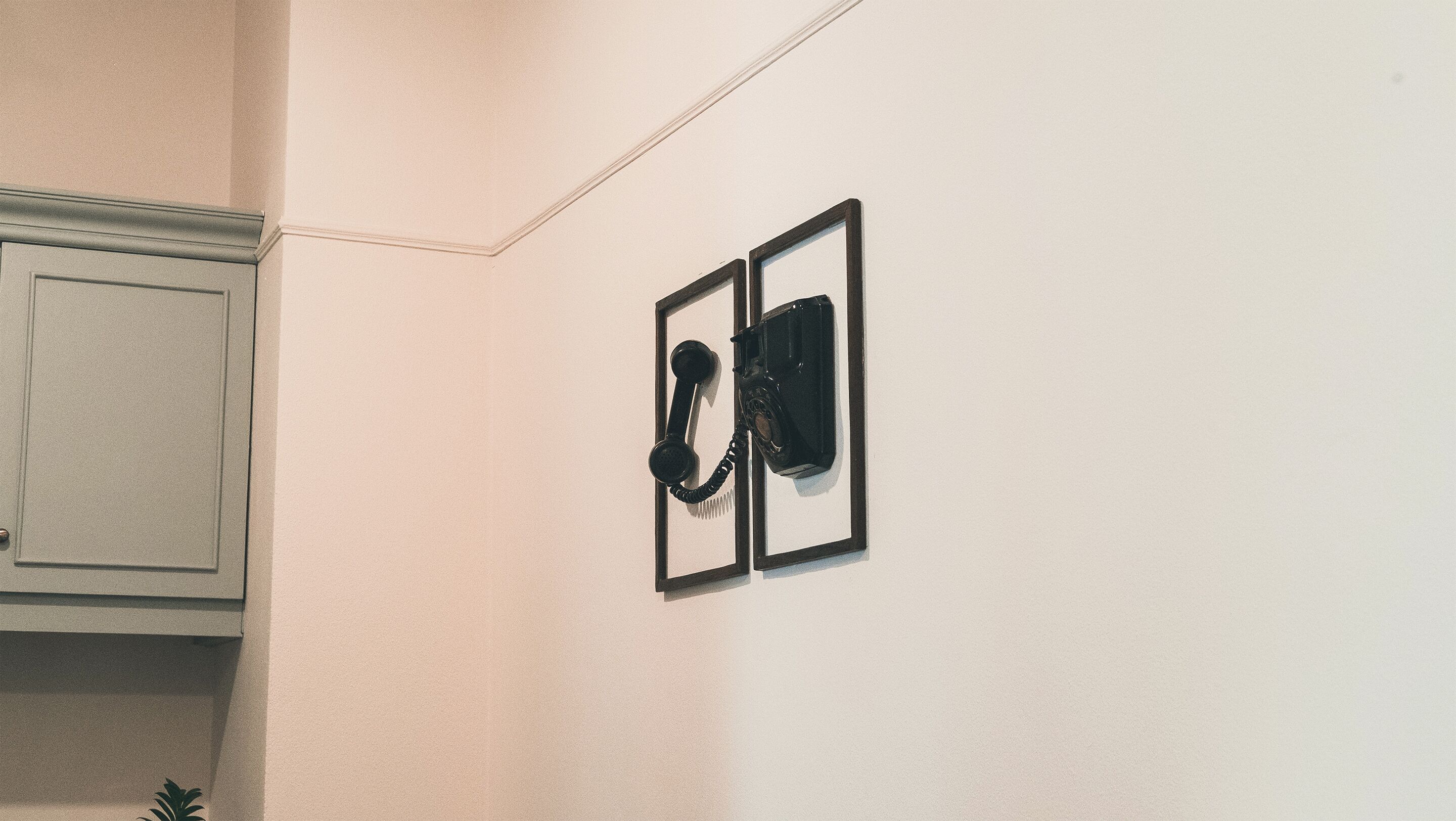 A wall-mounted telephone and a cabinet in a room.
