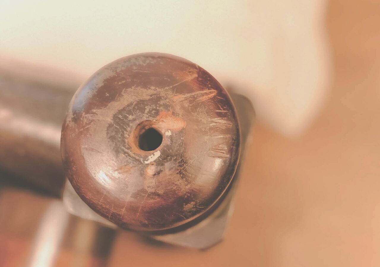 A close-up of a metallic object with a circular hole and some scratches.