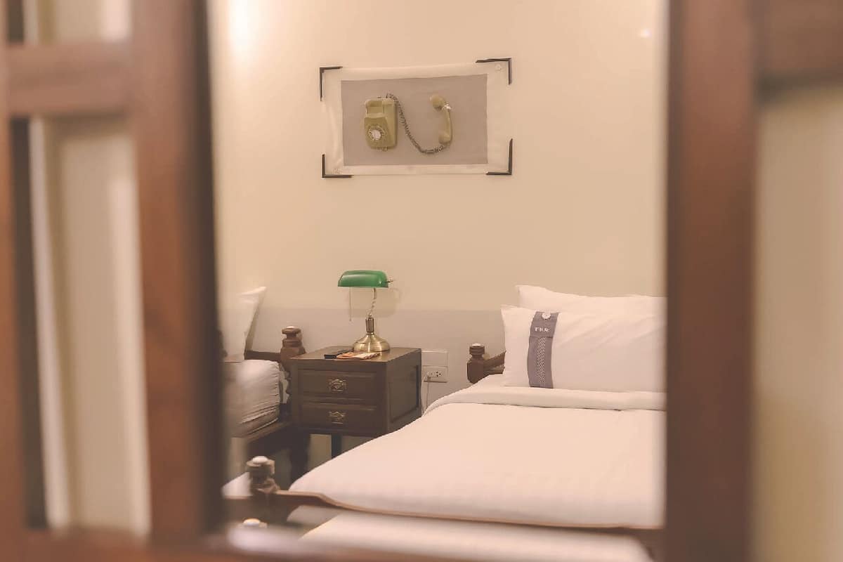 A hotel room with a bed, a nightstand with a lamp, and a framed picture on the wall.