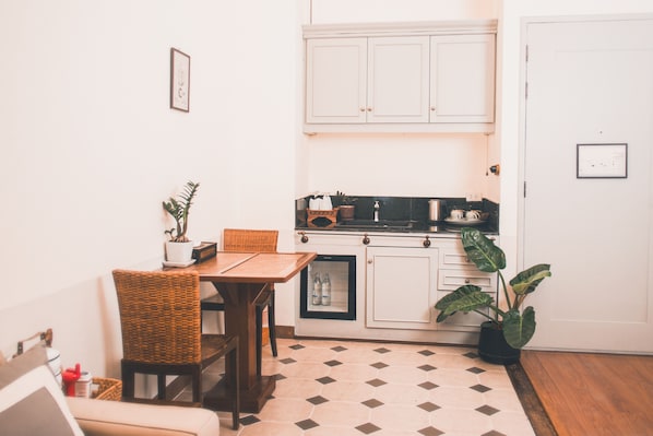 A compact kitchen with a dining table, chairs, a refrigerator, and a potted plant. - Yesterday Hotel (Chiang Mai)