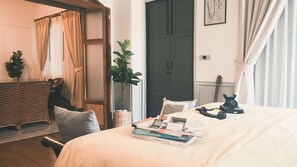 A bedroom with a bed, a bedside table with books, a telephone, a guitar, and a plant. - Yesterday Hotel (Chiang Mai)