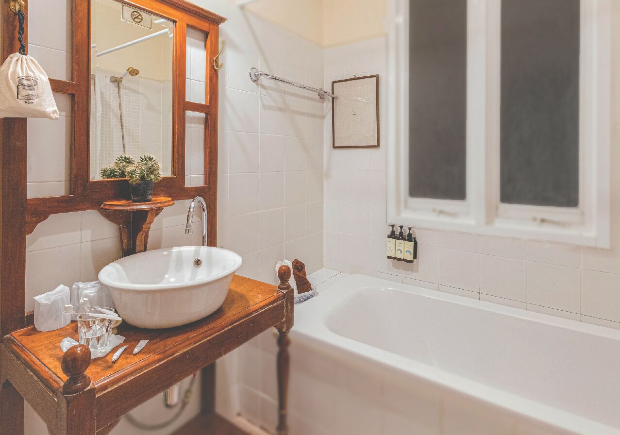 Un baño con tocador de madera, lavamanos blanco y bañera.