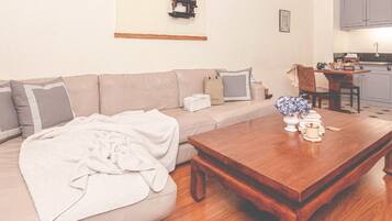 A living room with a sofa, coffee table, and a kitchen area in the background.