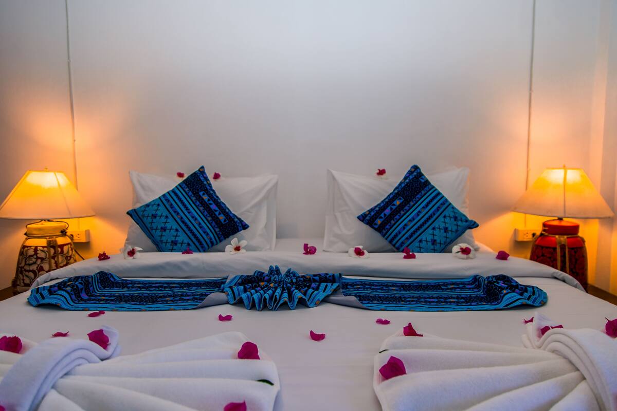 A neatly made bed with blue and white bedding, two pillows, and a decorative headboard.