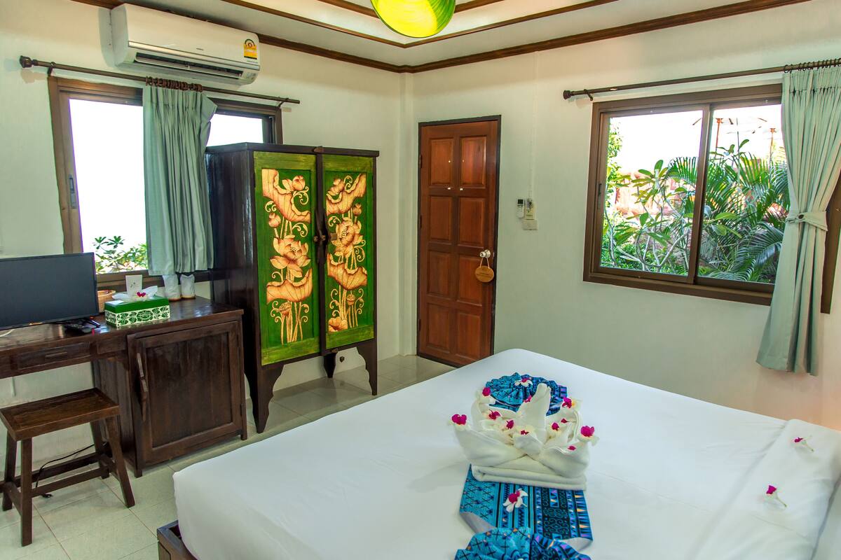 A hotel room with a bed, a desk, a television, a wardrobe, and a window with curtains.
