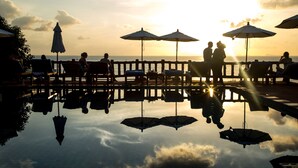 A serene poolside area with umbrellas and lounge chairs, reflecting the sky and clouds. - Zama Resort (Ko Pha-ngan)