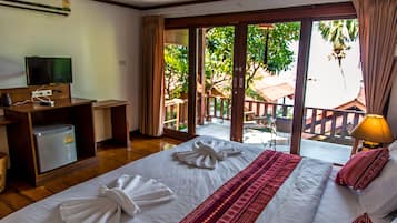 Quarto de hotel com cama, escrivaninha com computador, televisão e pequeno frigorífico.