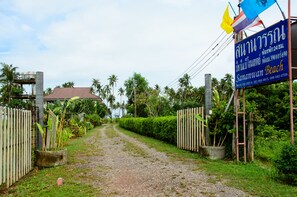 A pathway leading to a property with a signboard displaying contact information and a flag. - Sananwan Beach B&B (Bang Saphan Noi)