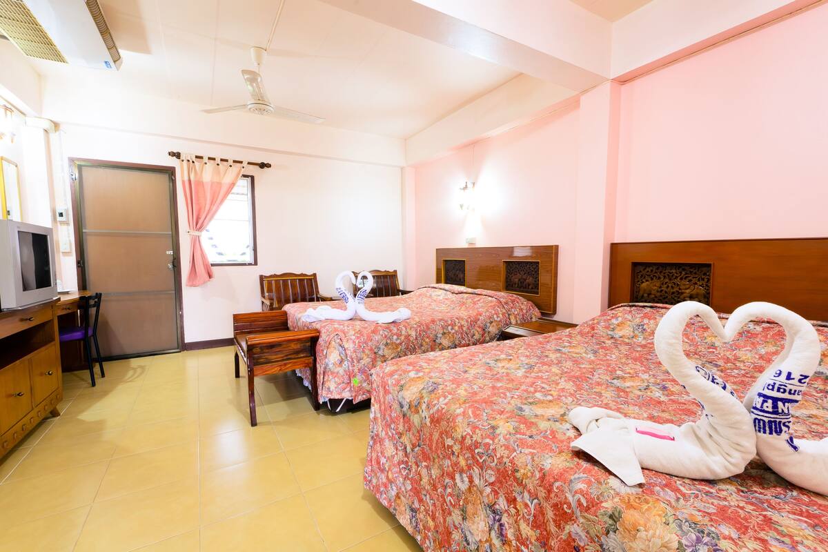 Une chambre d’hôtel avec deux lits, un bureau, une télévision et une porte.