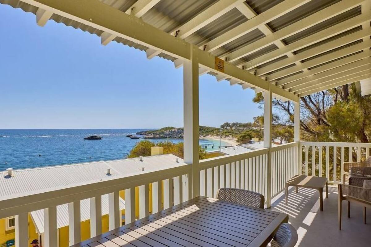 Ein Balkon mit Blick auf das Meer, einem Tisch und Stühlen.
