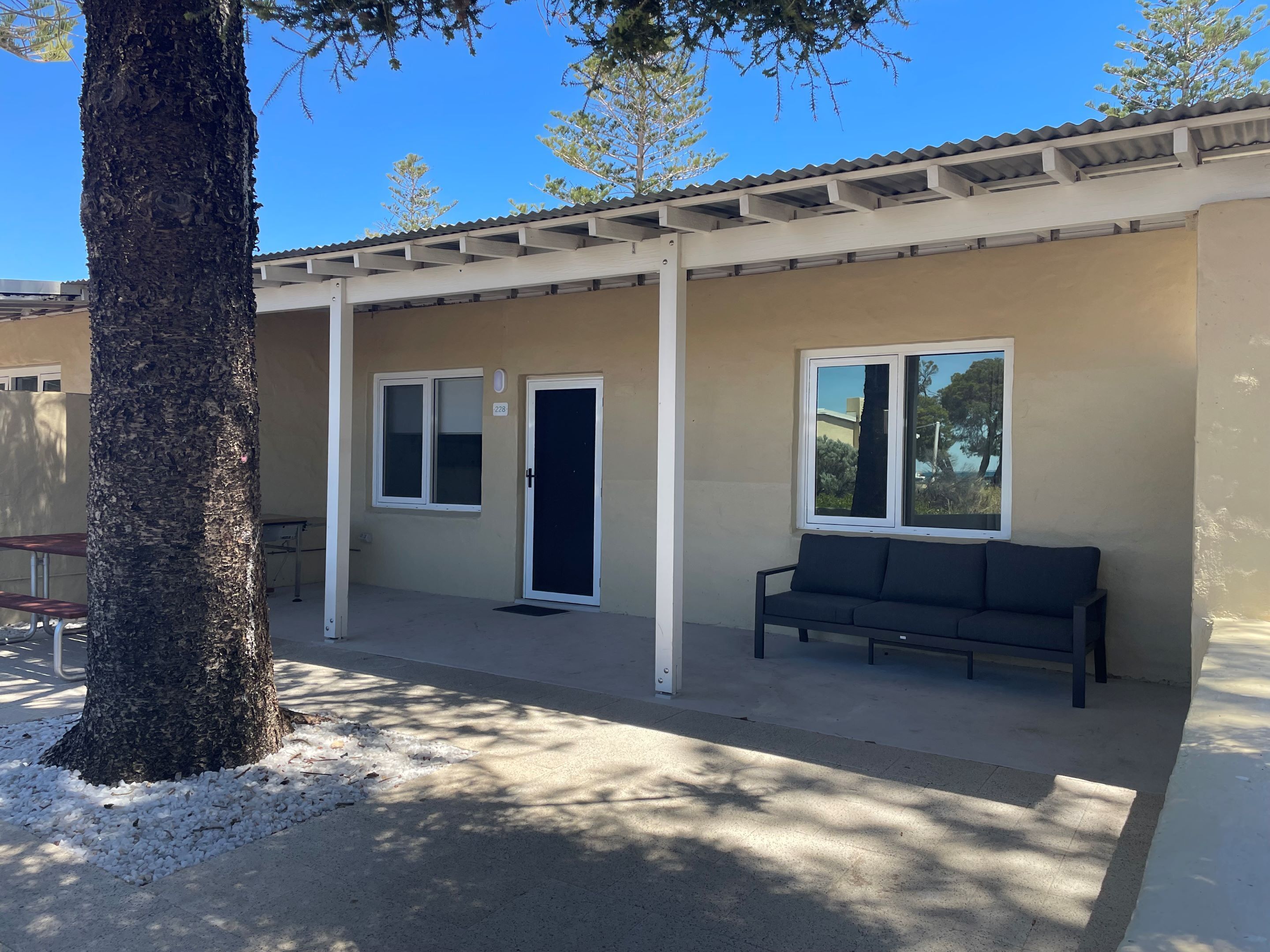 A building with a beige exterior, a black door, and a window with a view of trees.