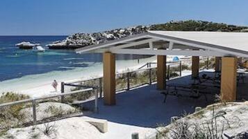 Relax under a shaded canopy overlooking the sandy beach and clear waters.