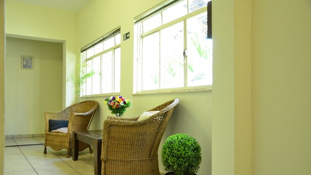 Una habitación con dos sillones de mimbre, una mesita y una planta en maceta.