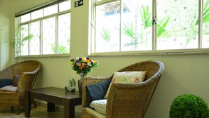 Una habitación con mobiliario de mimbre, una mesa y una planta en maceta.