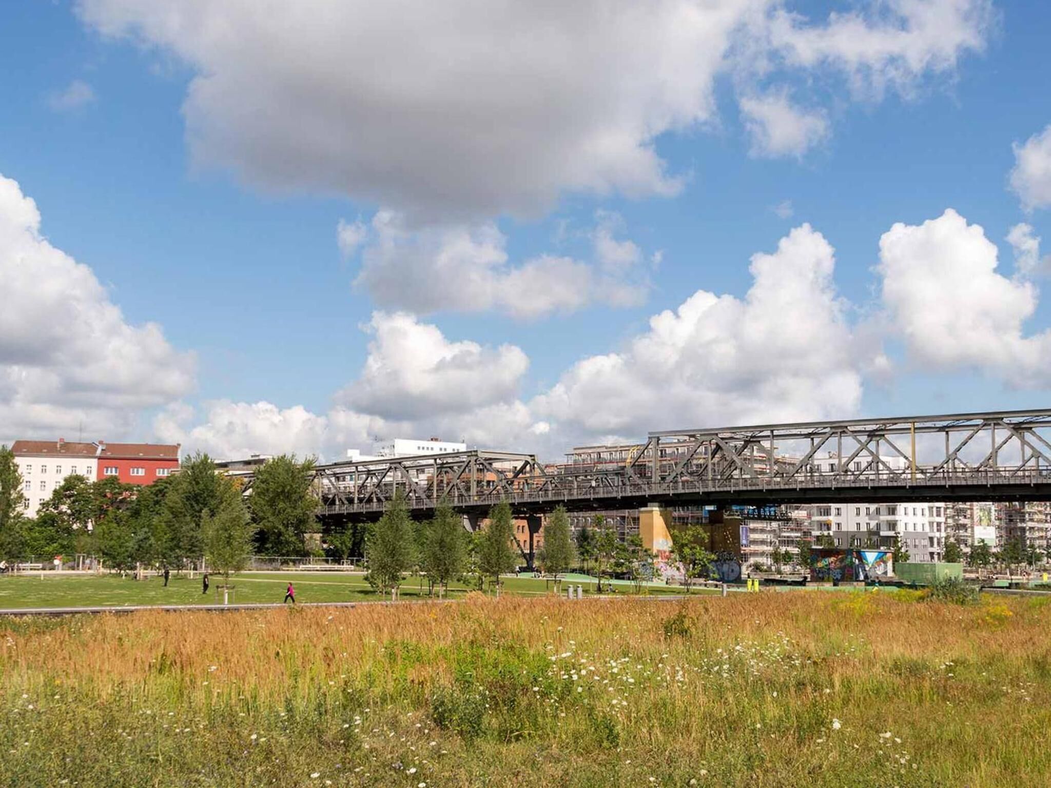 Un puente sobre un campo, con edificios al fondo.